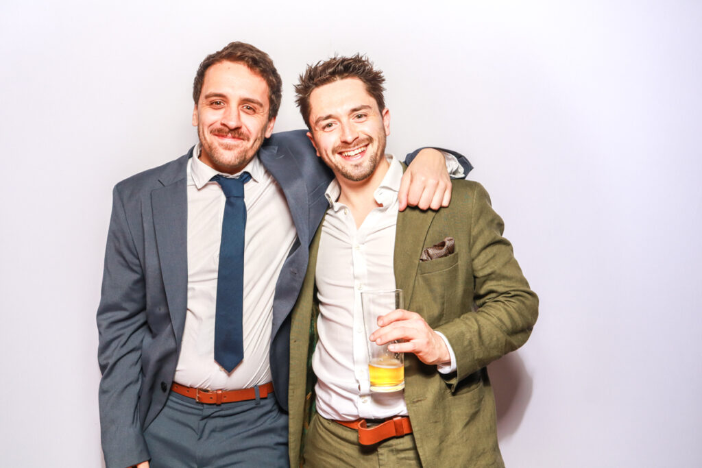 2 guests posing against a white backdrop during a corporate event entertainment for mad hat photo booth