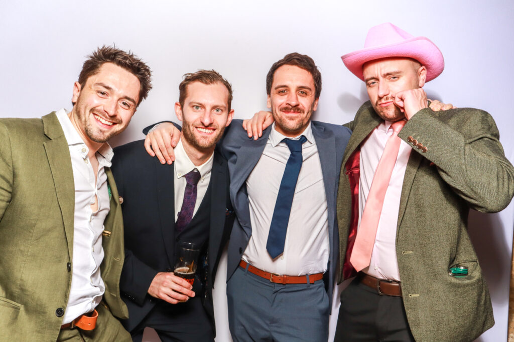 4 guys posing against a white backdrop during a corporate event photo booth hire, with mad hat photo booth rental services