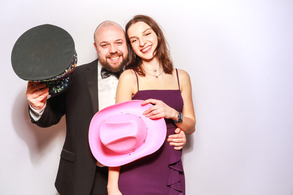 2 guests posing against a white backdrop during a corporate event entertainment for mad hat photo booth