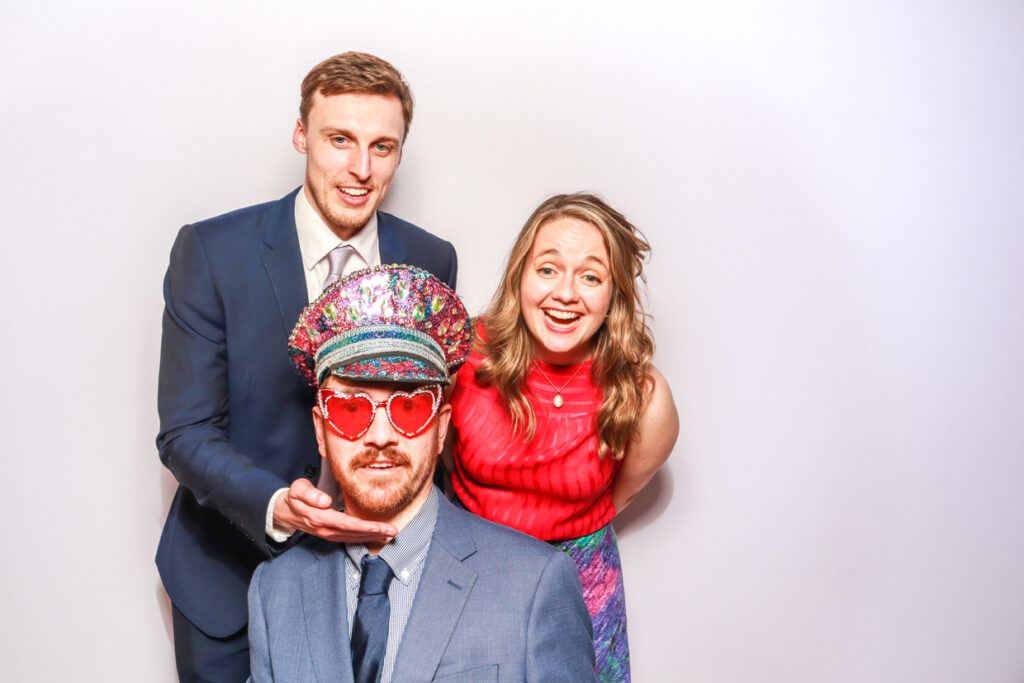 3 guests posing against a white backdrop during a corporate event entertainment for mad hat photo booth