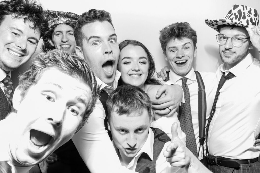 black and white image of large group of people during a party entertainment photography moment, posing against a white backdrop for a christmas corporate party