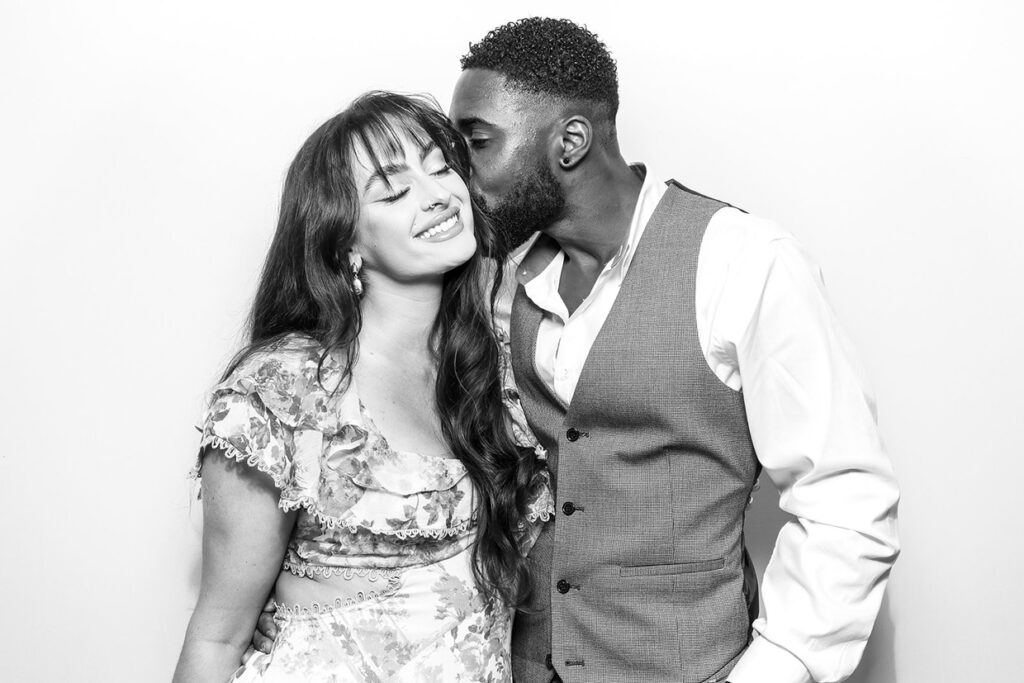 black and white print of 2 guests posing against a white 
 background, during a private party event with an Affordable Christmas Photo Booth Rental for weddings and corporate parties