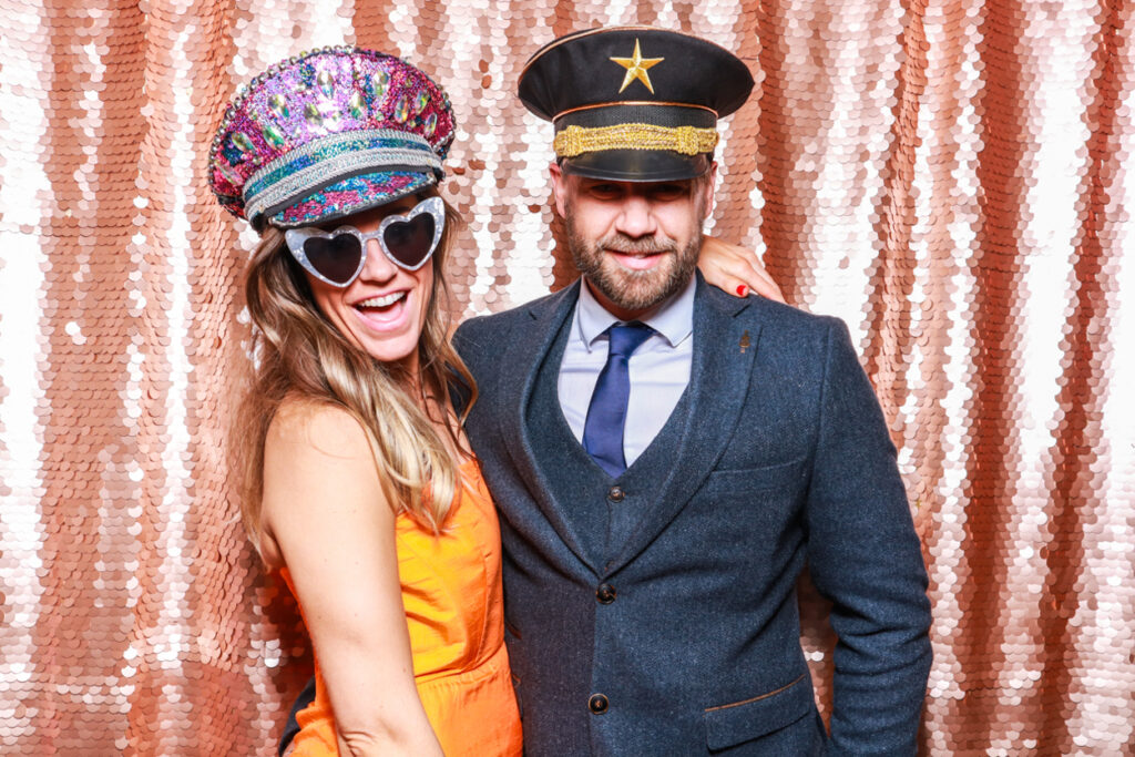 2 guests during an event for brands posing against a blush sequins backdrop with fancy props