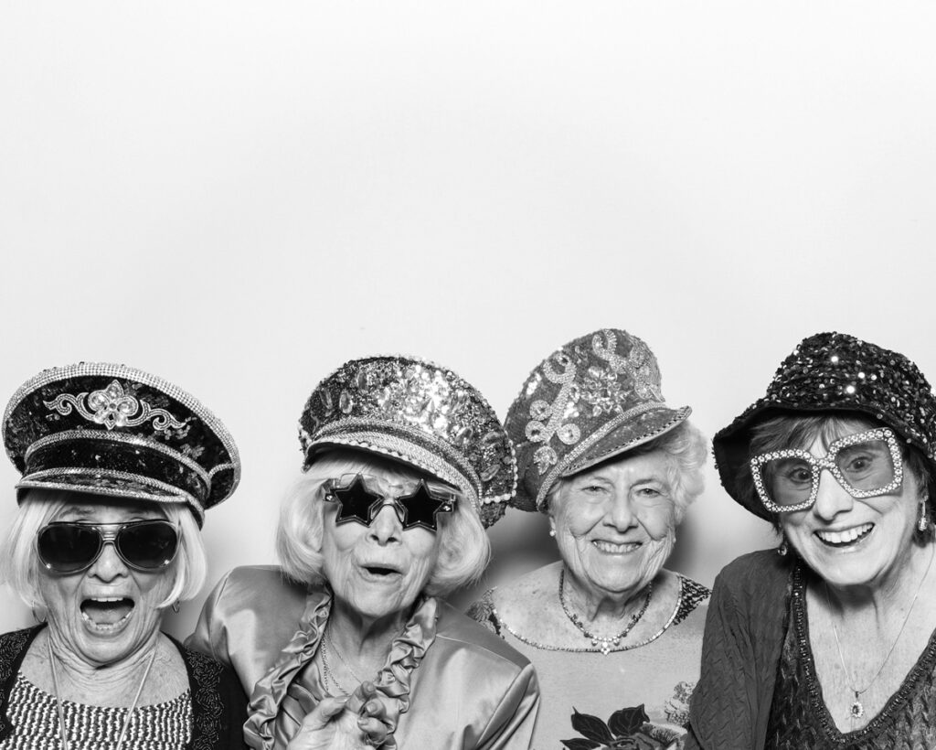  b&w photo of 4 elder guests posing and having fun with sequins hats at the The Great Barn Aynho Wedding Photo Booth with  mad hat photo booth rental Banbury