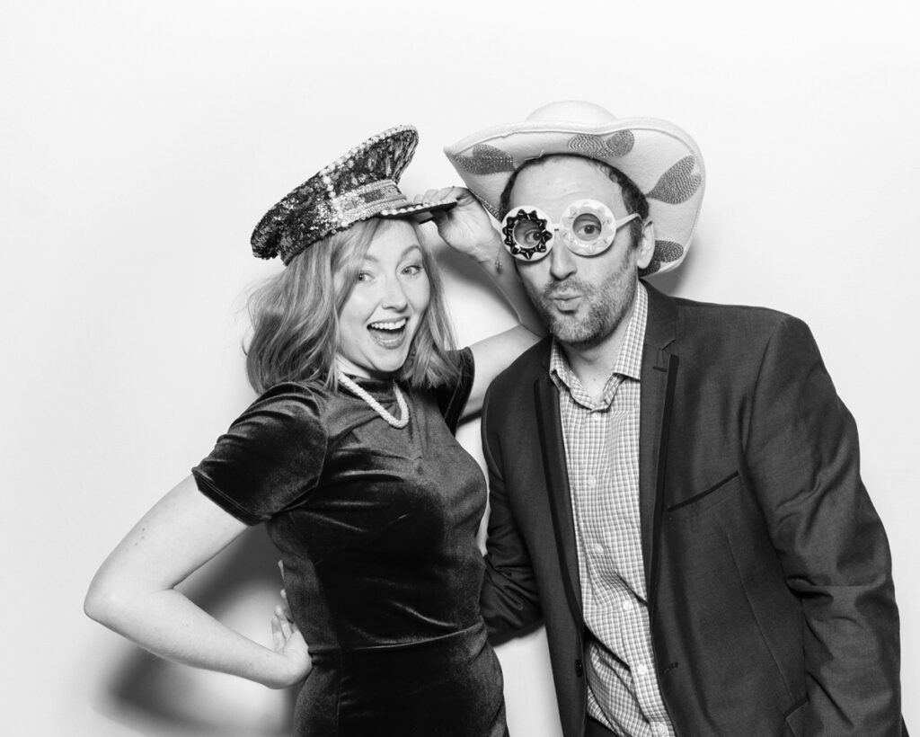 b&w photo of best wedding party entertainment during a reception event at Banbury barn in Oxfordshire, with mad hat photo booth rental