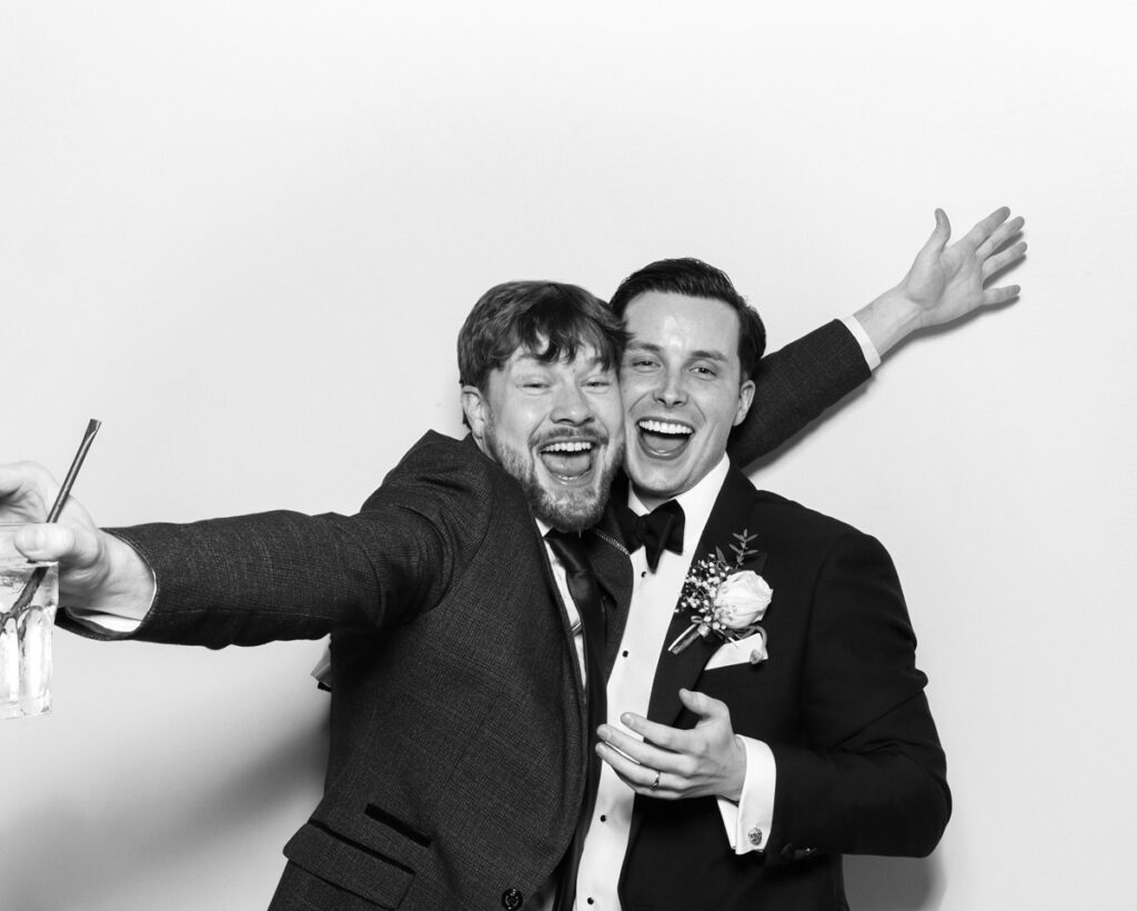 b&w photo of 2 guests in tuxedos posing and laughing during an event entertainment with the best photo booth rental in Oxfordshire