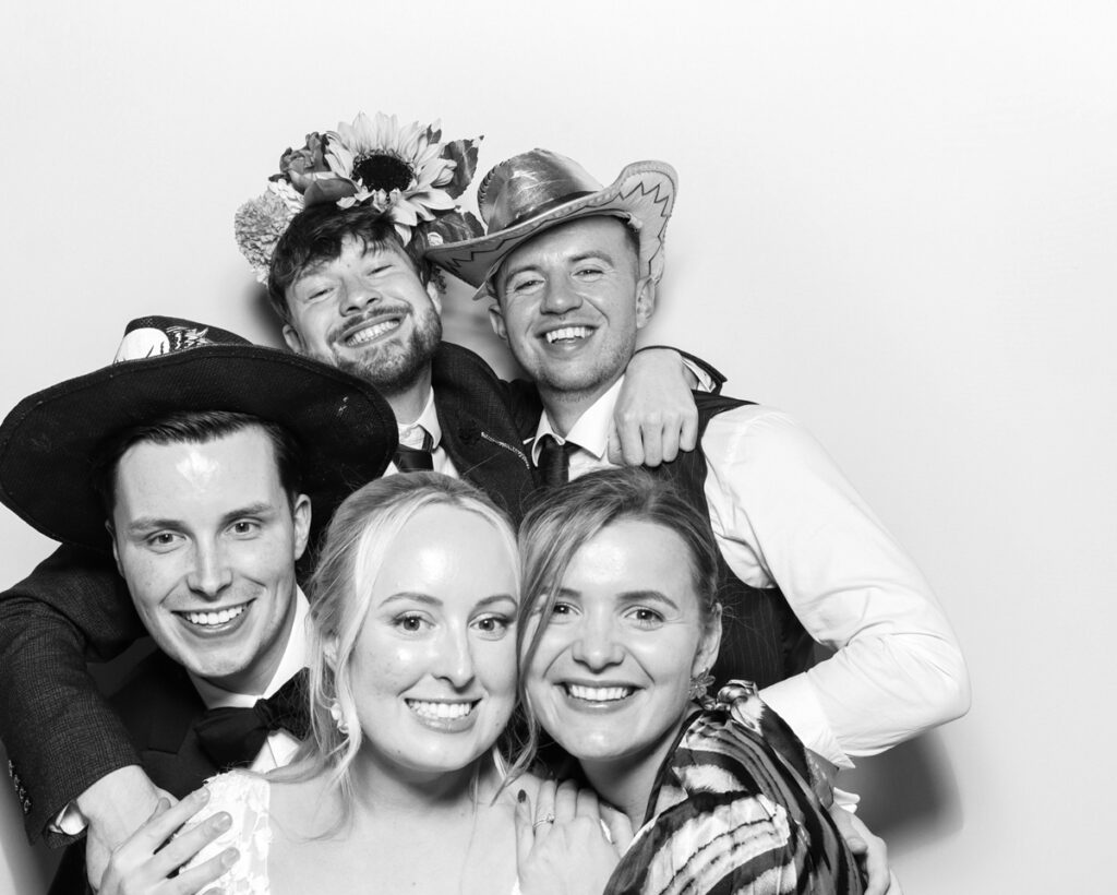 b&w photo of 5 guests posing and having fun with sequins hats and props during a wedding party entertainment with  mad hat photo booth rental in Banbury