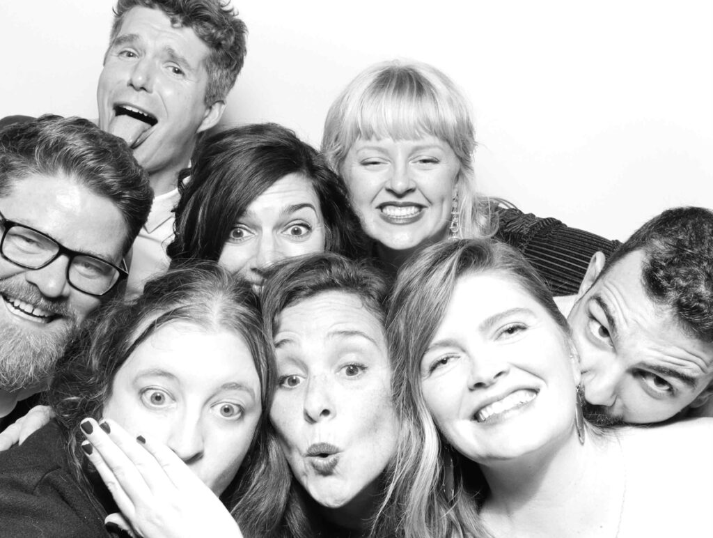 A lively group of people posing for a Cripps Barn photo booth picture, with exaggerated facial expressions and wide smiles.