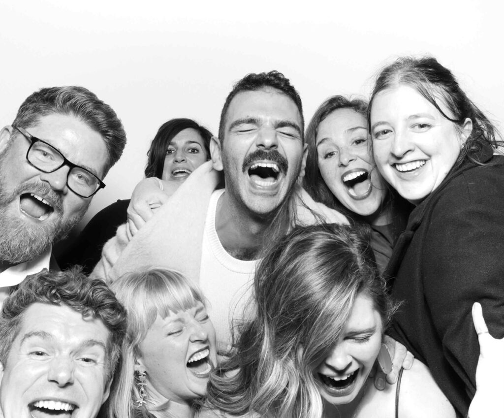 A cheerful group of friends captured in a Cripps Barn photo booth, laughing and enjoying a fun moment together.