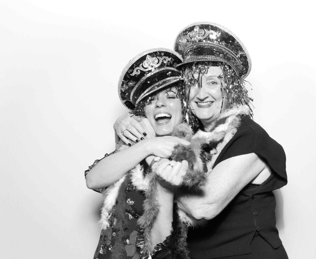 A fun and energetic moment in the Cripps Barn photo booth as guests accessorised with sequinned hats and feather boas strike playful poses.