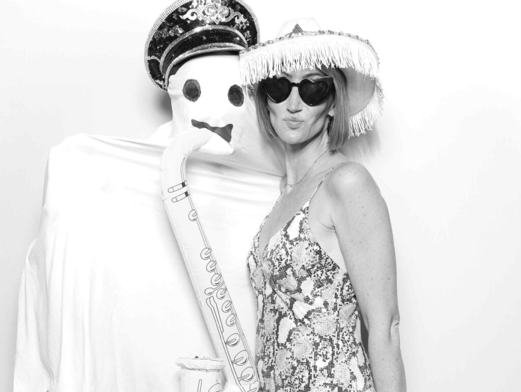 A black-and-white photo of a guest playfully leaning in towards a ghost-like figure during a creative photo booth session.

