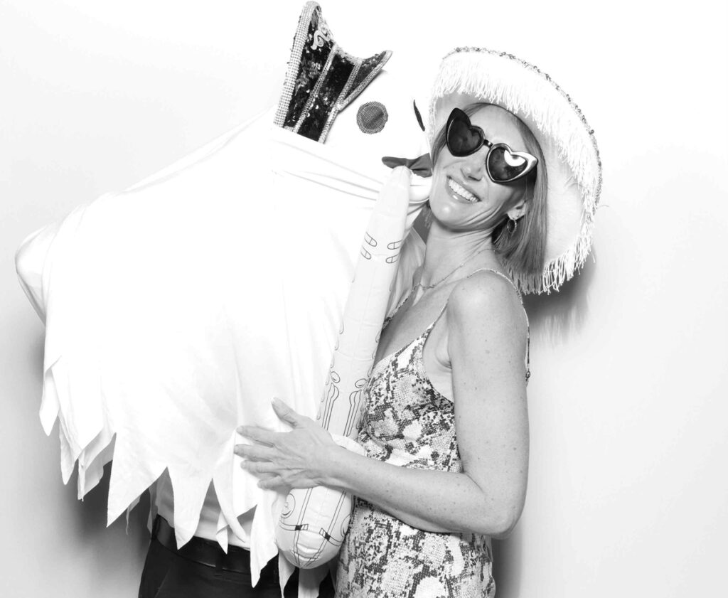 A creative black-and-white photo featuring a guest posing with a ghost-like figure holding an inflatable saxophone at Cripps Barn.