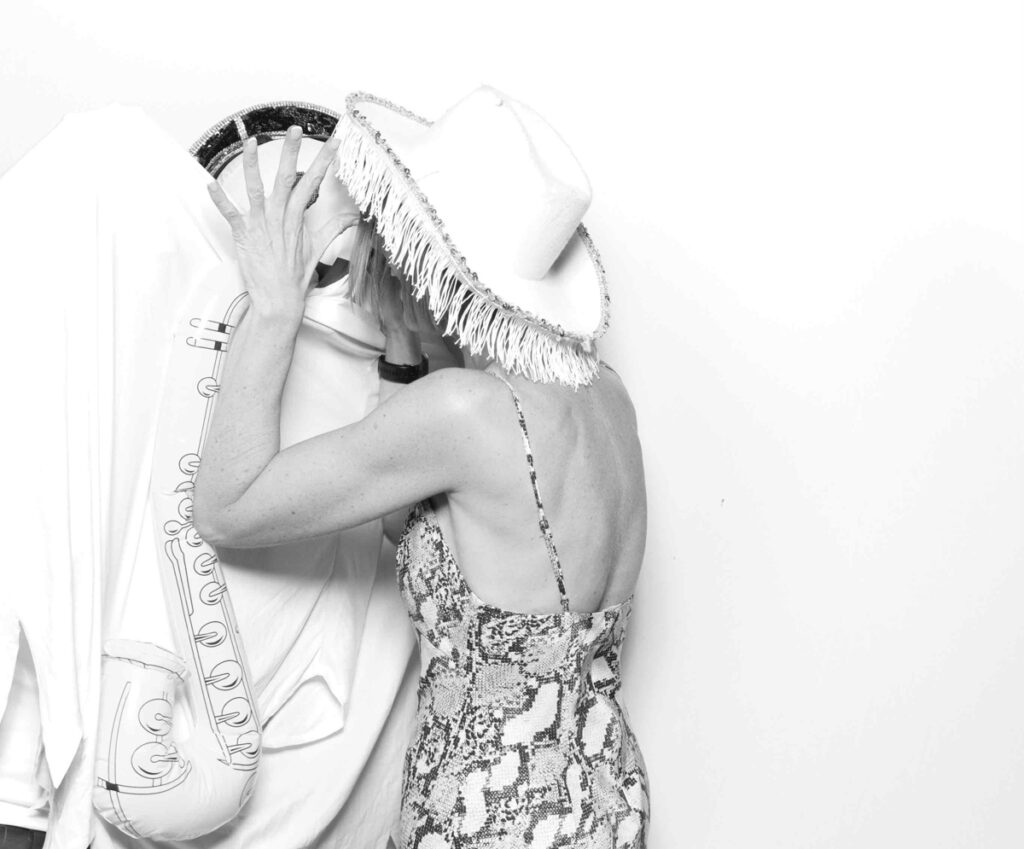 A wedding guest laughing and interacting with a ghost-themed figure in a humorous photo booth setup.