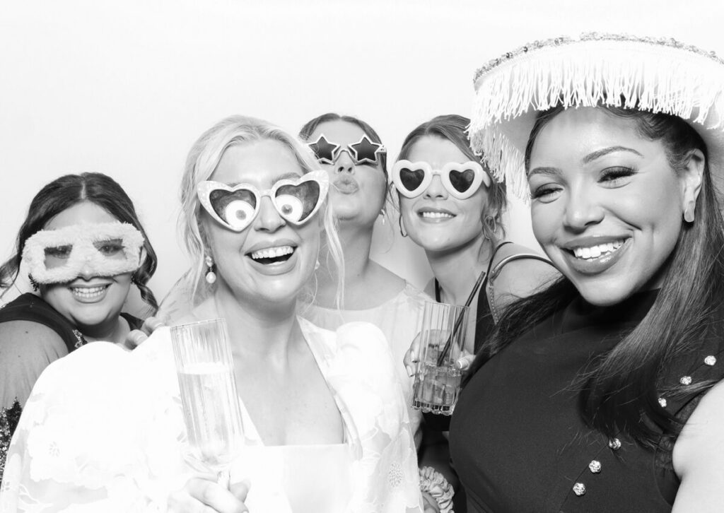 friends with bride in a black and white image posing for a luxury wedding photo booth rental