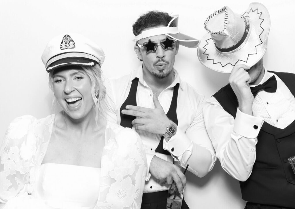 guests posing with props for a luxury photo booth hire at Kin house standing  against a white backdrop with a kardashian style photo booth print