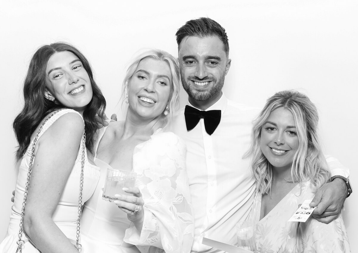 b&w print of 2 couples posing against a white backdrop for the party entertainment during the reception for kin house luxury venue