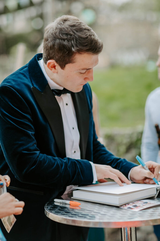 guests during a corporate event entertainment, writing notes in a custom guest book 