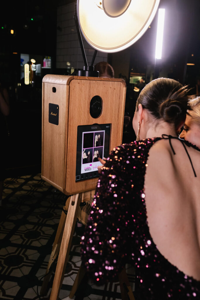 wedding guests during a reception party , having fun with the photo booth hire and getting their instant print 