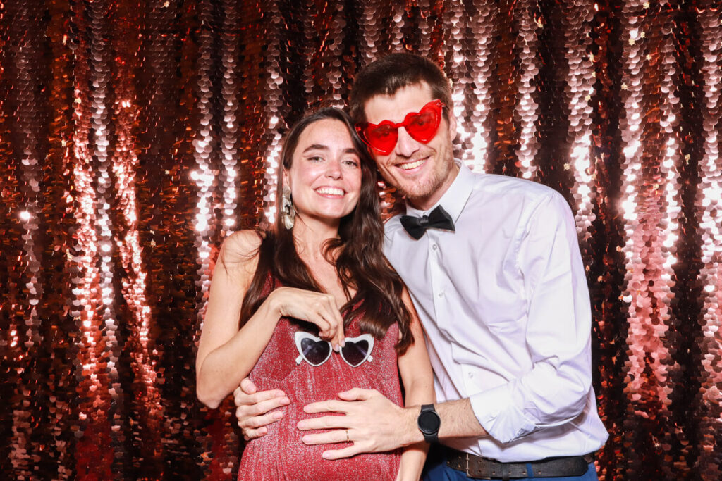 guests during a party entertainment evening, posing with heart shaped sunglasses, against a sequins backdrop, for party entertainment hire and rental in bristol