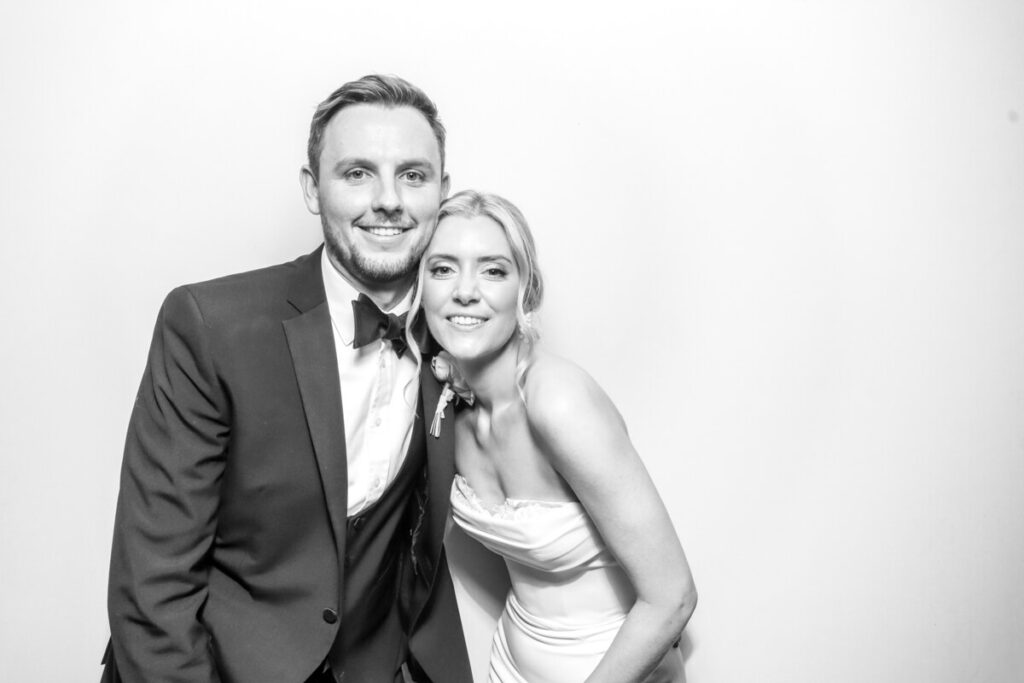 bride and groom posing against a white backdrop, during a wedding photo booth hire in Oxford for their party entertainment