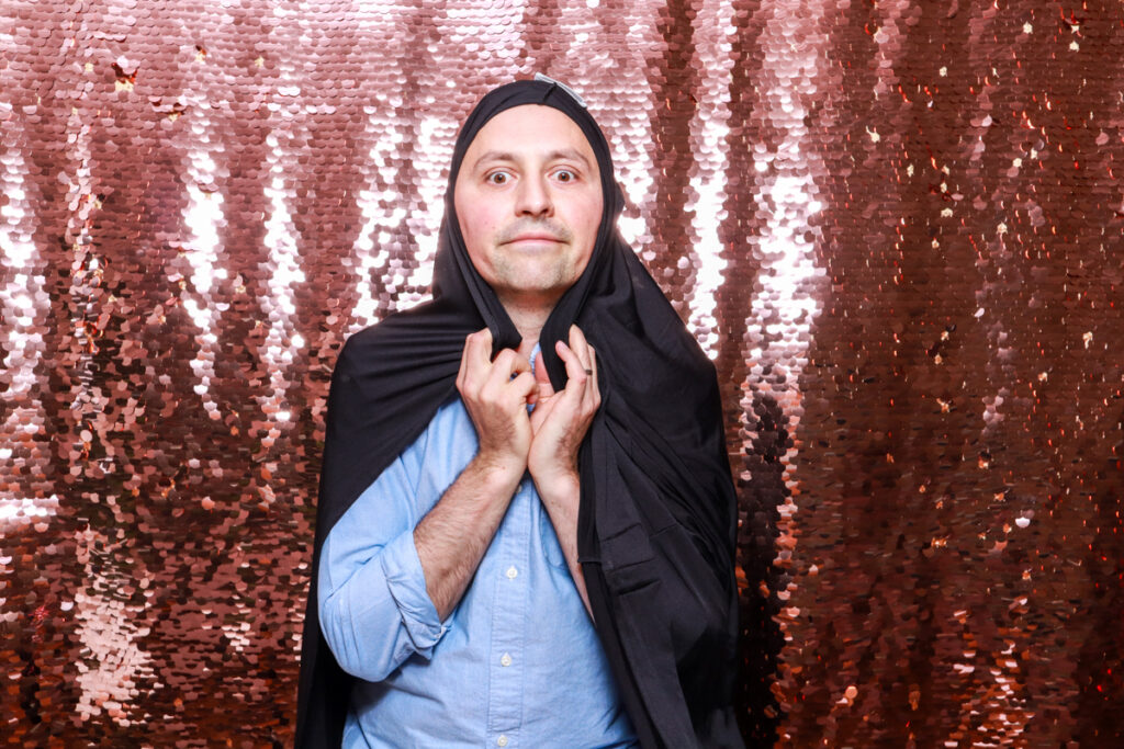 1 guest posing with a suit over his head against a champagne sequins backdrop, for a birthday party entertainment hire in Cotswolds area