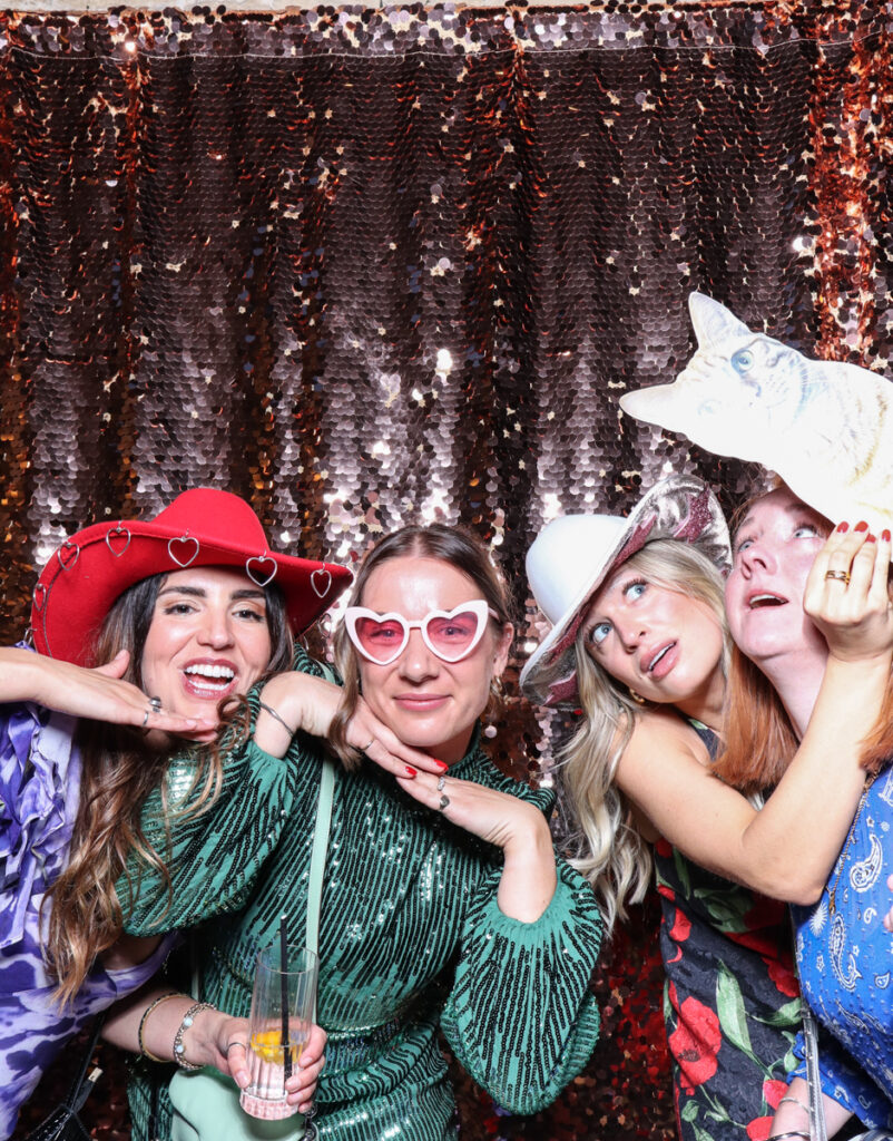 large group of guests posing with super fun props, against a champagne sequins backdrop, for a cotswolds wedding party entertainment with mad hat photo booth hire for parties, birthdays and weddings