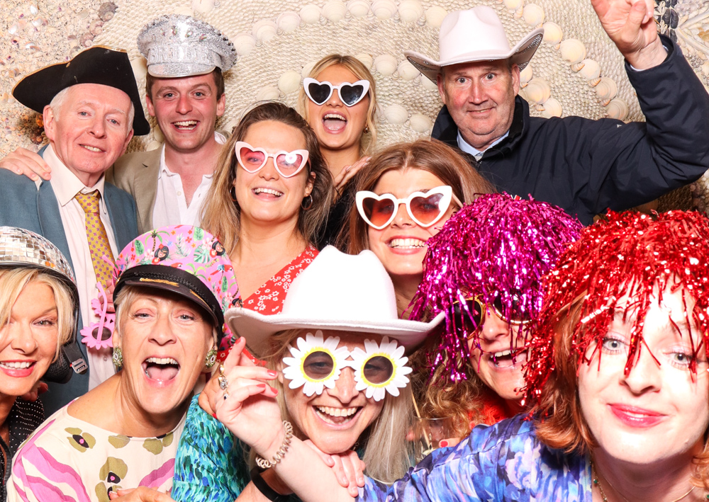Large group photo filled with colourful wigs, novelty hats, and wide smiles during a lively photo booth moment at Belcombe Court
.