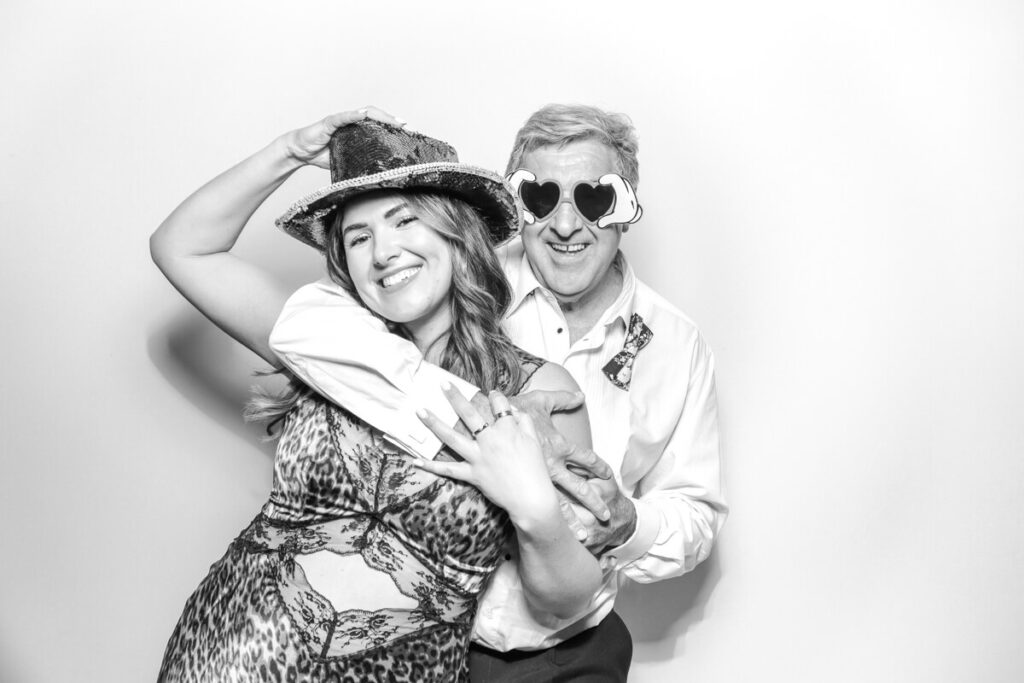 Wedding guests wearing fun hats and heart-shaped glasses in the black and white photo booth at a Kiftsgate Court Gardens celebration.