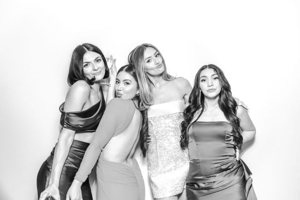 Four glamorous female guests posing together in the black and white photo booth at a Kiftsgate Court Gardens wedding.