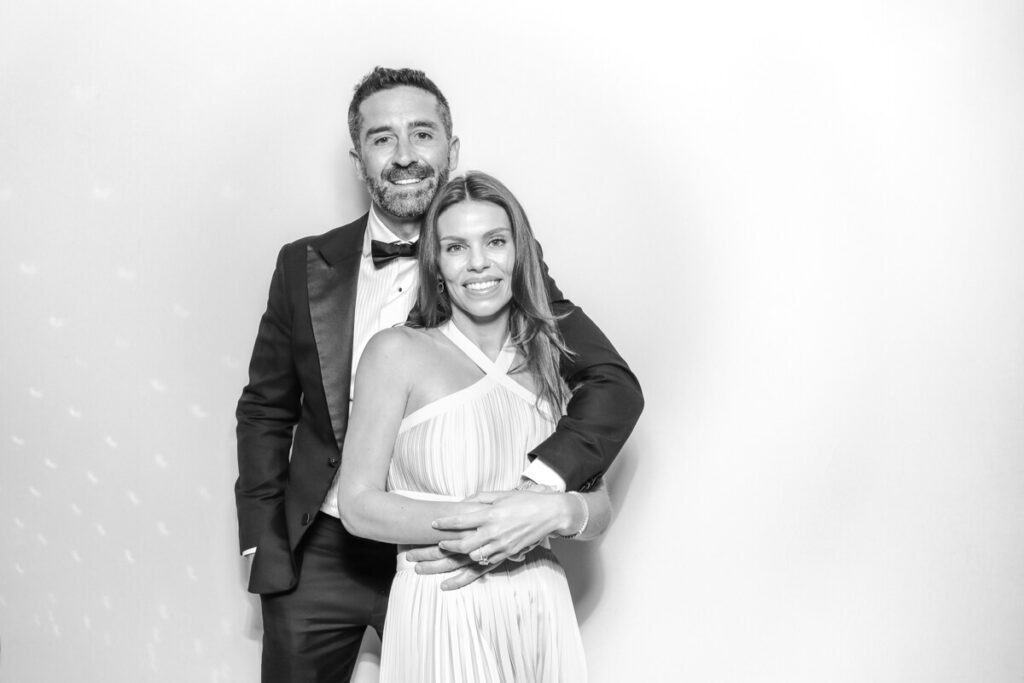couple smiling and embracing inside a black and white photo booth at a Kiftsgate Court Gardens wedding near Chipping Campden.