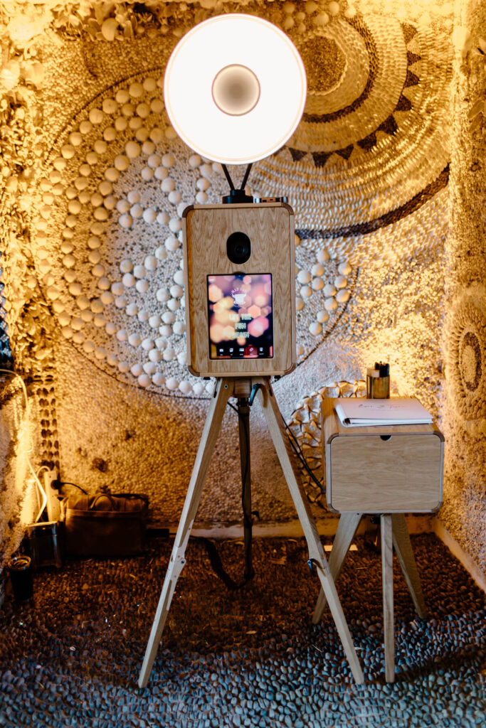 Full frontal view of the Icon photo booth framed by intricate shell patterns on the walls of Belcombe Court’s garden pavilion.