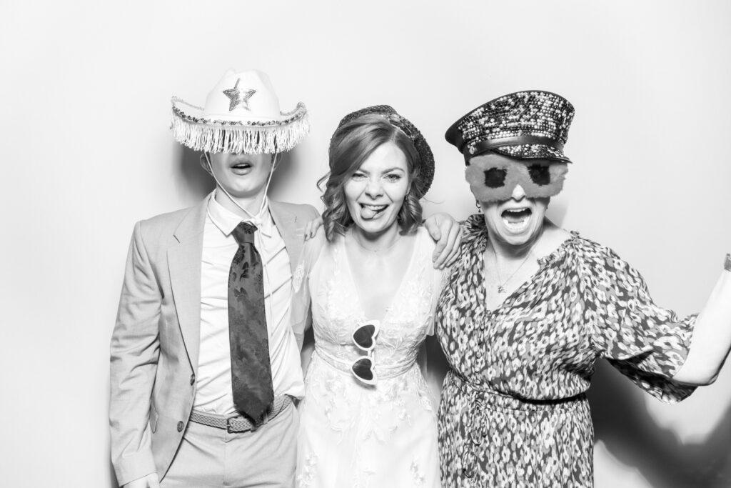 one male guest posing with a wig prop on his head, posing against a white backdrop with a b&w filter for kardashian style selfie pod hire for a photo booth hire affordable party entertainment
