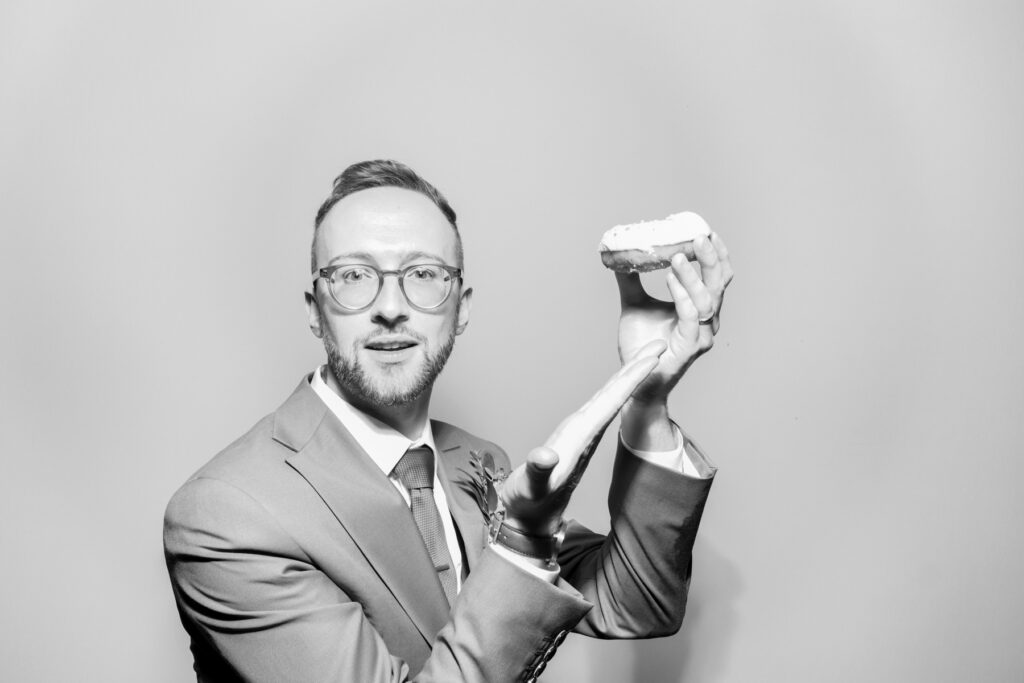one male guest posing with a wig prop on his head, posing against a white backdrop with a b&w filter for kardashian style selfie pod hire for a cheltenham photo booth hire affordable party entertainment