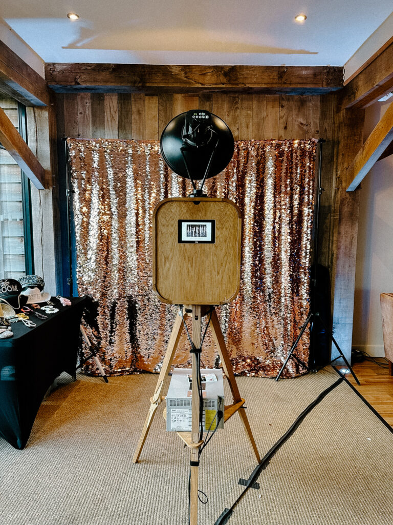 retro open photo booth setup with a wooden photo booth and a champagne sequins backdrop, at a cotswolds wedding venue