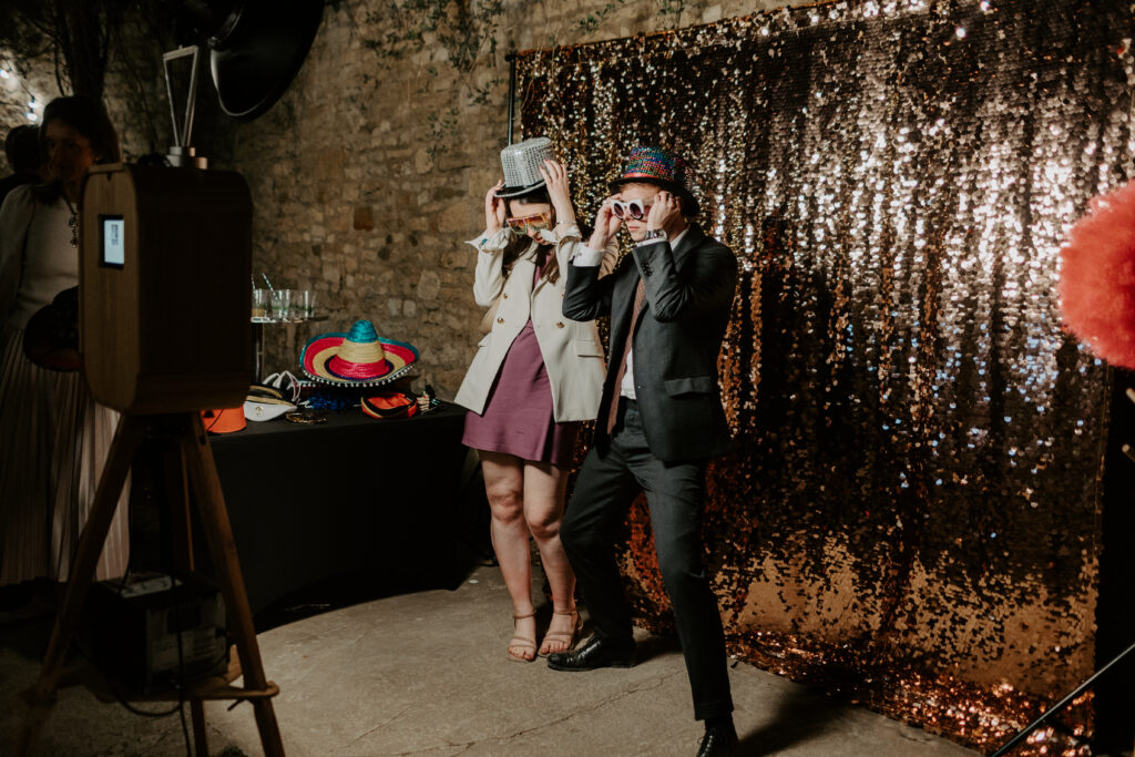 2 guests posing for a photo booth with a champagne sequins backdrop in the back, for an outdoor photo booth hire