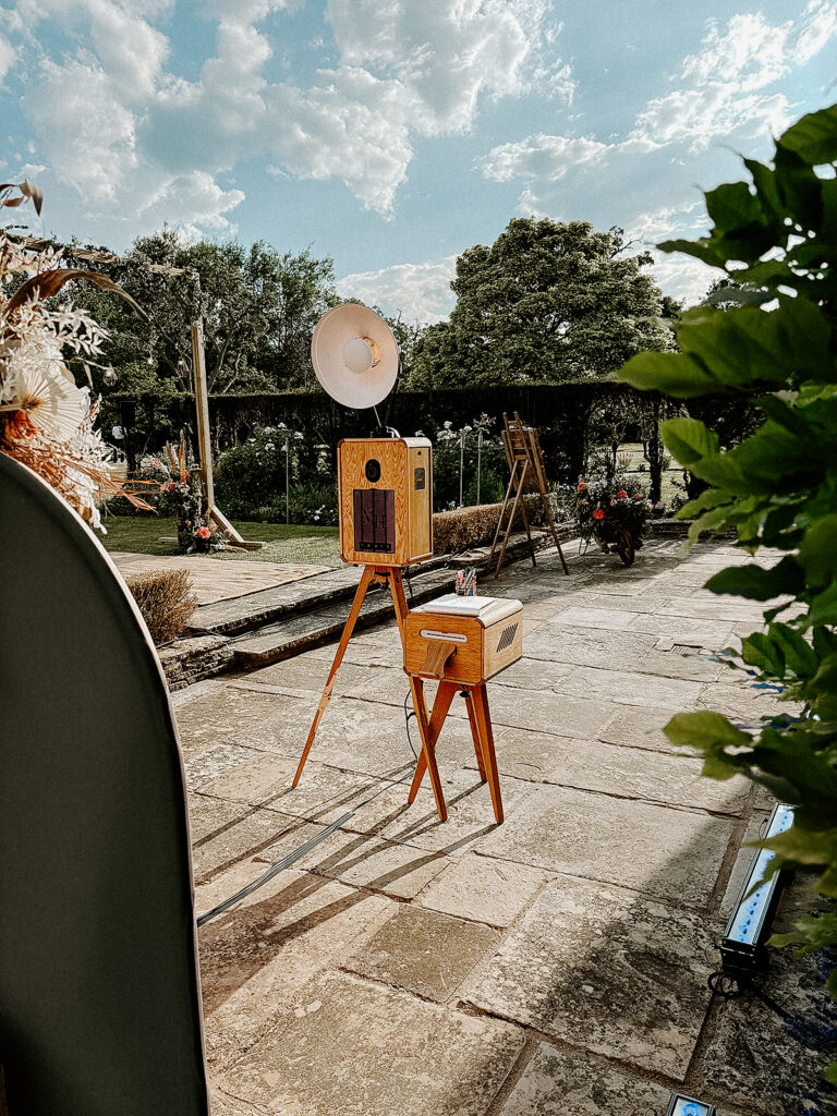 premium wooden outdoor photo booth with summer arches backdrop during an outdoor garden party in the summer in cotswolds