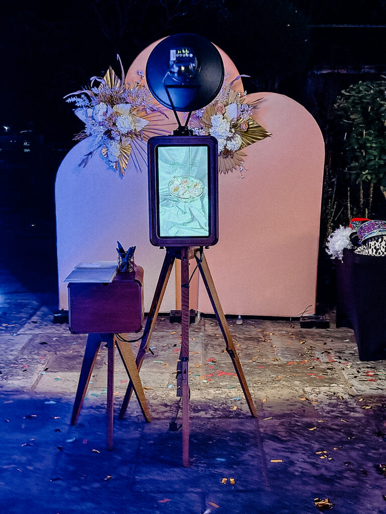 wooden outdoor photo booth with summer arches backdrop during an outdoor garden party in the evening in the summer in cotswolds