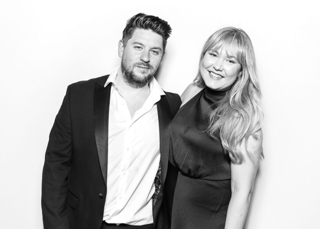 A couple smiling together at Eastnor Castle, captured in a clean and classic black and white photo booth image.