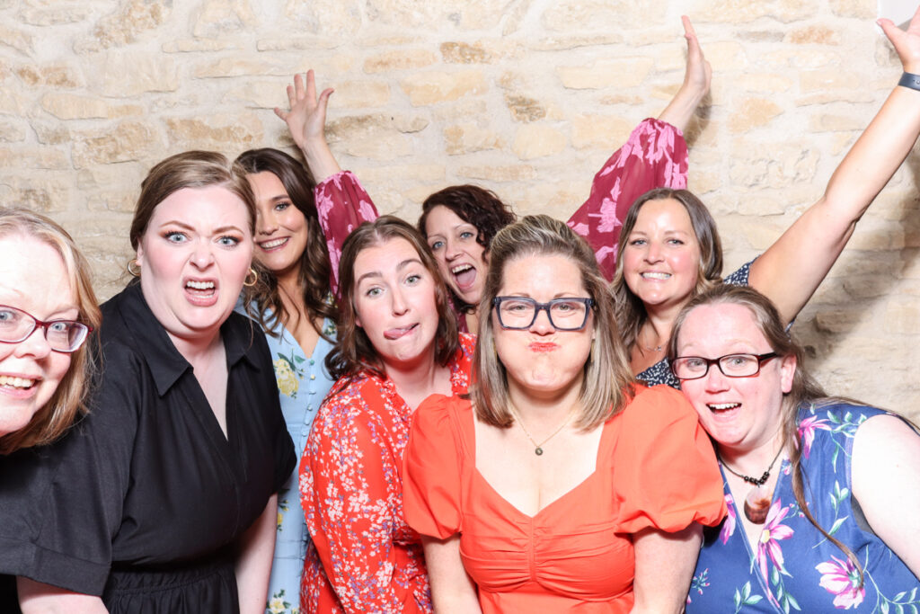 Group of women pulling funny faces and posing in a vibrant photo booth session