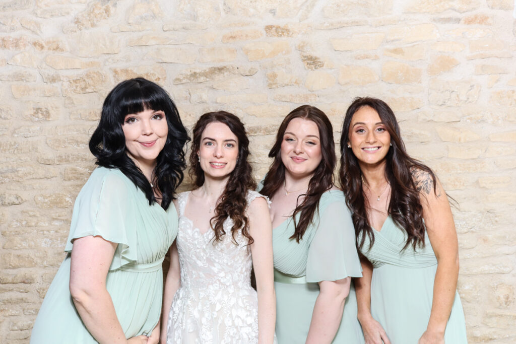 Bride with bridesmaids in mint green dresses at a Cotswolds wedding photo booth