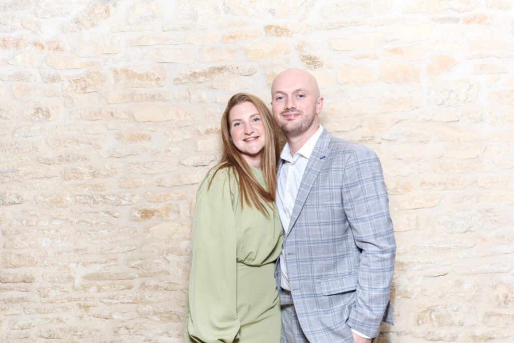 Couple dressed in green and grey outfits posing at a relaxed wedding photo booth