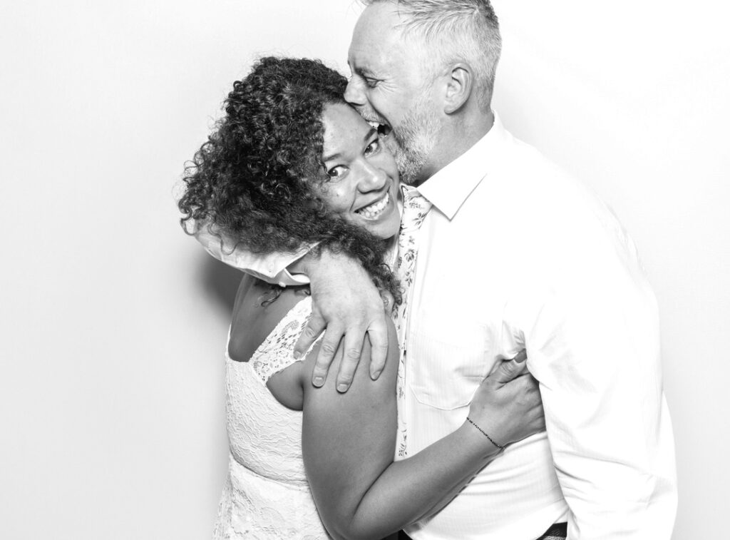 couple posing against a white backdrop, with a b&w photo booth hire in bristol , for the best party entertainment