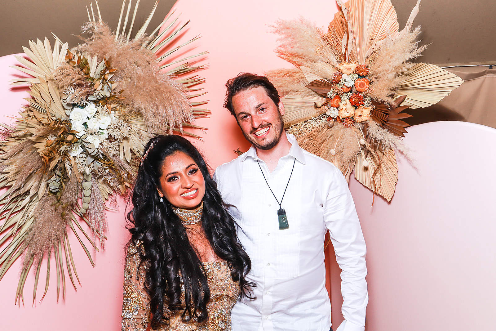 Luxury Asian wedding couple in photo booth with dried floral backdrop at Euridge Manor in the Cotswolds