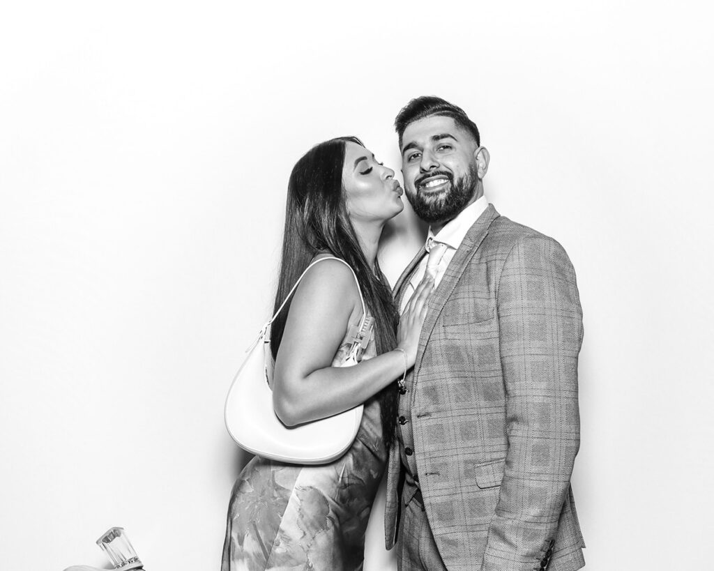 Couple posing in Kardashian-style luxury Asian weddings photo booth with clean white backdrop