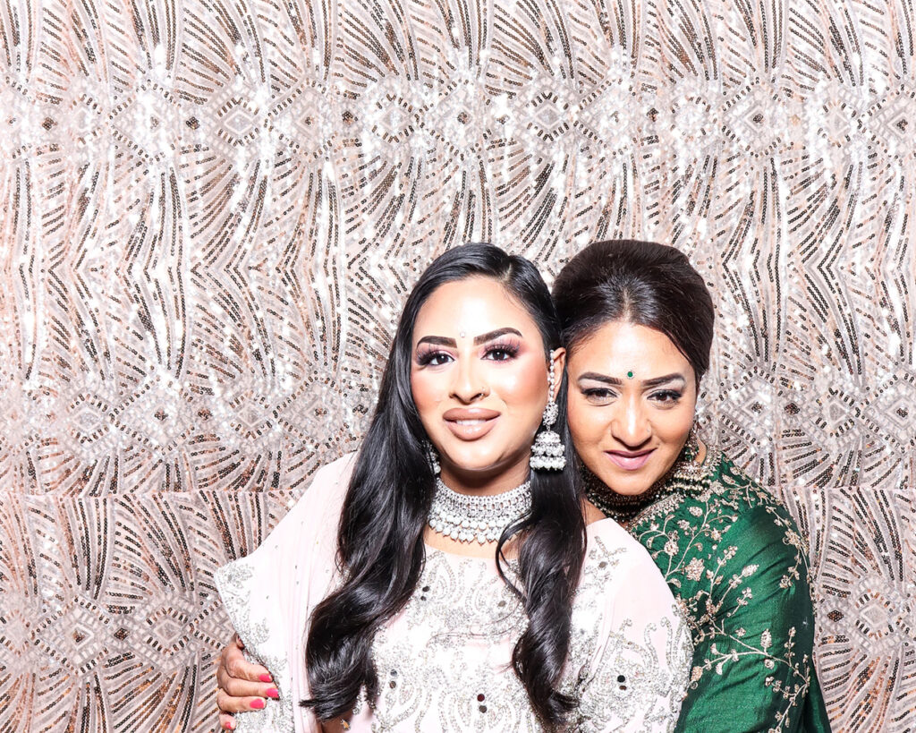 Mother and daughter sharing a candid moment inside luxury Asian weddings photo booth at a cultural celebration