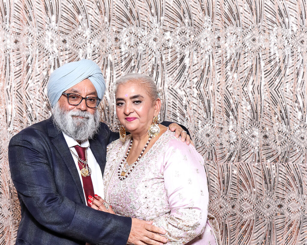 Elegant senior guests posing in a luxury Asian weddings photo booth with formal wear and sparkling backdrop