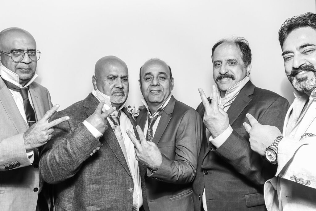 Wedding guests sharing peace signs in a fun, Kardashian-style black and white wedding photo booth moment with classic suits during an Asian wedding party entertainment