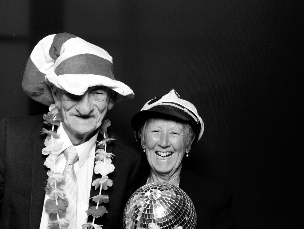 older couple posing against a black backdrop during a wedding party entertainment in stroud , by the best photo booth to hire near me