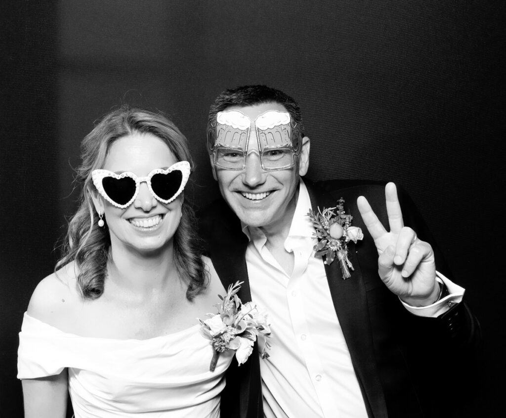 bride and groom posing against a black backdrop, for a Chic Black & White Photo Booth Wedding at The Painswick Hotel in stroud
