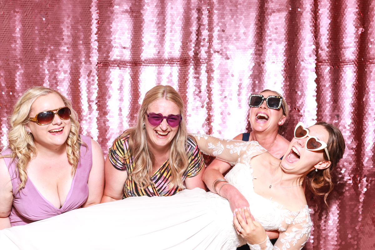  friends lifting the bride in the air during a photo booth picture against a lilac sequins backdrop, for the best photo booth for hire in Worcester
